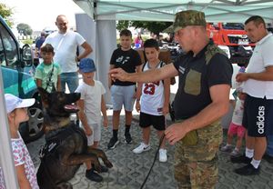 Pies służbowy z przewodnikiem, obok dzieci