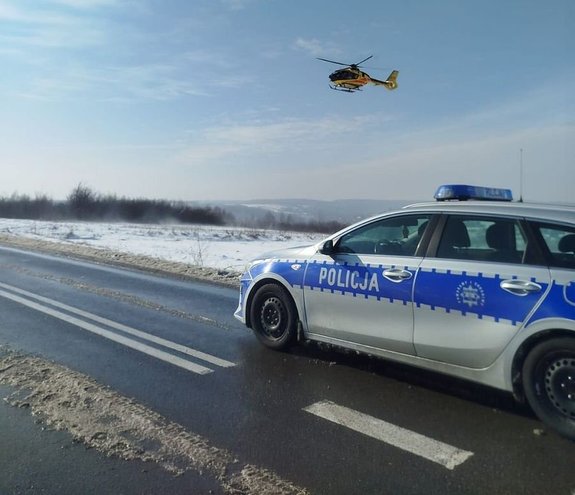 Radiowóz na drodze. W tle śmigłowiec LPR