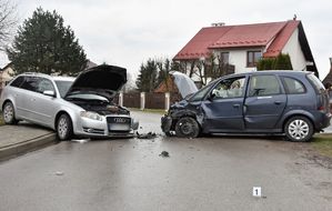 Miejsce zderzenia dwóch pojazdów na drodze. Samochody mają uszkodzona karoserię w przedniej części.