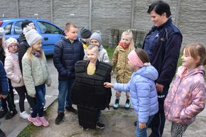 Policjantka z  dziećmi. Jeden z chłopców ma założoną kamizelkę ochronną