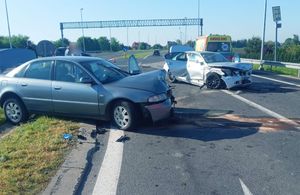 Samochody uszkodzone w wyniku wypadku drogowego. Pojazdy znajdują się na poboczu i na jezdni.