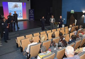 Sala kinowa. Na scenie stoją policjanci biorący udział w debacie. Na krzesełkach siedzą uczestnicy spotkania.