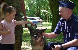 Policjant i dziewczynka.Obok dziewczynki znajduje się pies