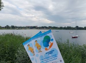 Ulotki bezpieczne wakacje, w tle zbiornik wodny