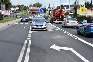 Miejsce wypadku drogowego - potracenia pieszego na przejściu dla pieszych. Na środku jezdni widoczny jest radiowóz. Po prawej stronie znajduje się wóz strażacki.