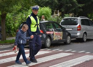 Policjant przeprowadza dzieci przez przejście dla pieszych