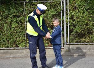 Policjant zakłada dziecku na rękę odblask