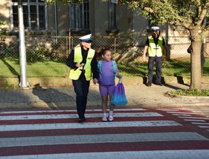 Policjantka przeprowadza przez przejście dziewczynkę