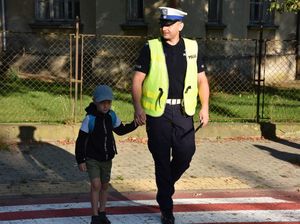 Policjant przeprowadza chłopca przez przejście dla pieszych