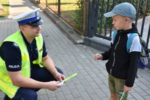 Policjant wręcza chłopcu odblaski