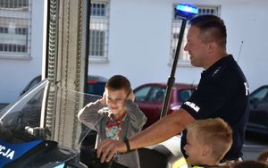 Chłopiec na motorze. Obok niego stoi policjant