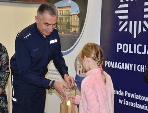 Policjant wręcza upominek dziewczynce