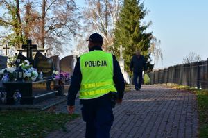 Policjant przechodzący alejką cmentarną