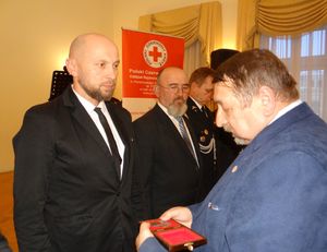 Mężczyzna wręcza pamiątkowy medal policjantowi