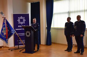 Komendant podczas przemówienia do nowych funkcjonariuszy. Obok dwóch policjantów.