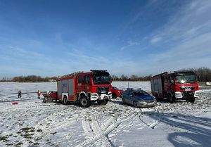 Wozy strażackie i radiowóz w okolicy zbiornika wodnego