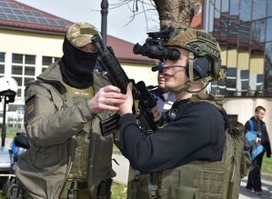 Policjant ze studentem ubranym w policyjne wyposażenie tj. kamizelkę i hełm