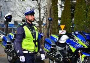 Policjant w czasie pełnienia służby na drodze. W tle policyjne motocykle