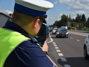 Policjant dokonuje pomiaru prędkości przejeżdżającym pojazdom