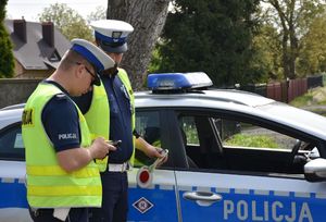 Policjanci przy radiowozie weryfikują dane kierującego pojazdem