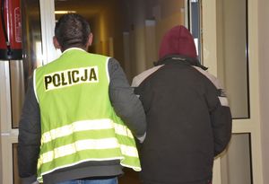 Policjant prowadzi zatrzymanego mężczyznę