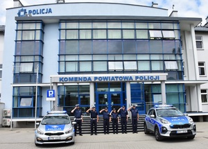 policjanci i radiowozy na tle budynku komendy policji