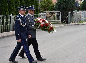 Policjanci idą w kierunku pamiątkowej tablicy