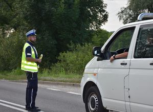 Policjant na drodze. Obok niego przejeżdża samochód.