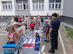 Policjantka z dziećmi na mobilnym miasteczku ruchu drogowego