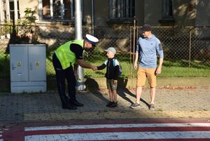 Policjant rozmawia z chłopcem przed przejściem dla pieszych