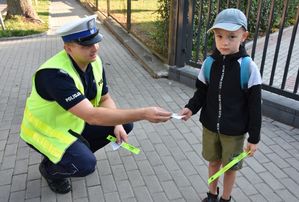 Policjant wręcza dziecku odblask