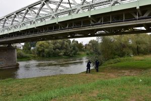 Policjanci monitorują stan wody na rzece w okolicy mostu