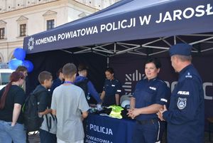 Policyjne stoisko przed którym znajdują się policjanci i odwiedzający to stoisko