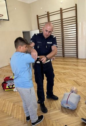 Policjant z chłopcem podczas zajęć praktycznych udzielania pierwszej pomocy.