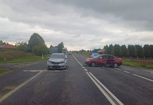 Miejsce wypadku drogowego. Na drodze stoją uszkodzone dwa pojazdy. W tle radiowóz