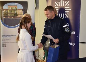 Policjant wręcza nagrodę dziewczynce