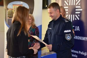 Policjant wręcza nagrodę dziewczynce