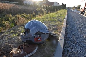 Kask motocyklisty lezy przy krawężniku drogi