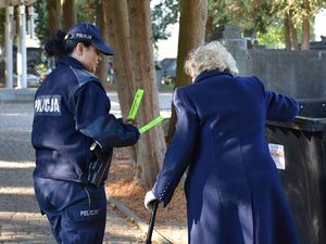 Policjantka przekazuje na cmentarzu starszej kobiecie odblaski