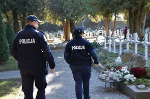 Policjant i policjantka idą cmentarną alejką