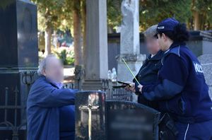 Policjantka przekazuje odblaski starszym osobom na cmentarzu