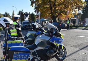 Polcicyjny motocykl. W tle policjanci kierują ruchem drogowym.