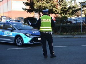 Policjant kieruje ruchem. na drodze widoczny jest radiowóz