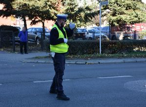 Policjant kieruje ruchem pojazdów na drodze