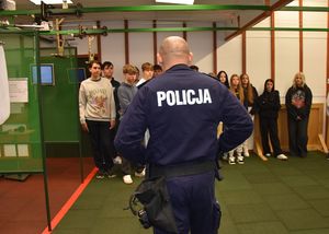 Policjant na strzelnicy prowadzi wykład dla licealistów