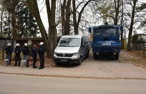 Policjanci podczas zabezpieczenia meczu. Obok bus oraz pojazd służbowy.