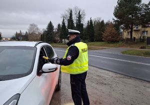 Policjant bada stan trzeźwości kierującego pojazdem