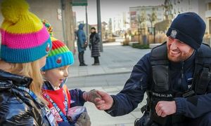 Dzieci - wolontariusze WOŚP. Obok dzieci  znajduje się policjant