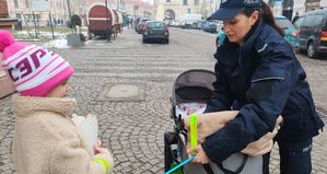 Policjantka zakłada odblask na wózek dziecięcy