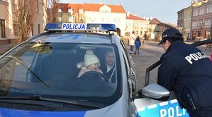 Policjantka przy radiowozie. Wewnątrz mężczyzna z dzieckiem